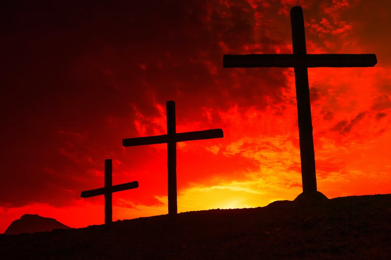 Three crosses on the background of the sunset red-yellow sky. The concept of the crucifixion of Jesus.